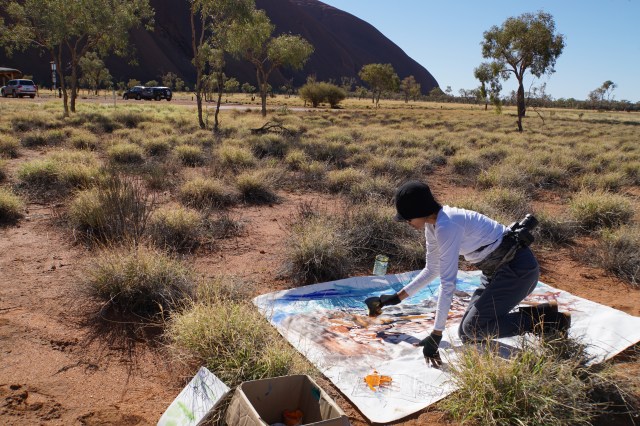 Artist Ni Nyoman Sani painting on location at Uluru. Image Made Budhiana
