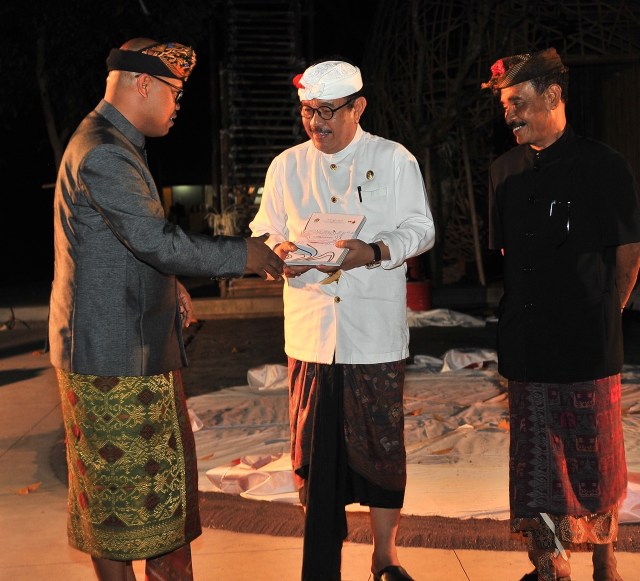 During the opening ceremony of Bali Megarupa 10 October 2019 at ARMA, Dr Wayan Kun Adnyana presents the Bali Megarupa exhibition catalog to Bali Deputy Governor Cokorda Ace as ARMA founder Agung Rai looks on. Image coutesy of Bali Megarupa.